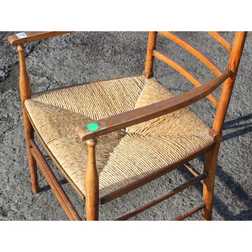 137 - In the manner of Liberty of London, an Arts & Crafts period oak ladder back armchair with rush seat