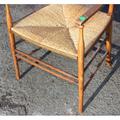 137 - In the manner of Liberty of London, an Arts & Crafts period oak ladder back armchair with rush seat