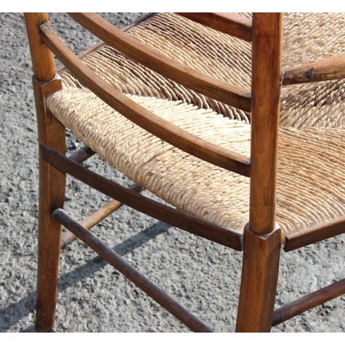 137 - In the manner of Liberty of London, an Arts & Crafts period oak ladder back armchair with rush seat