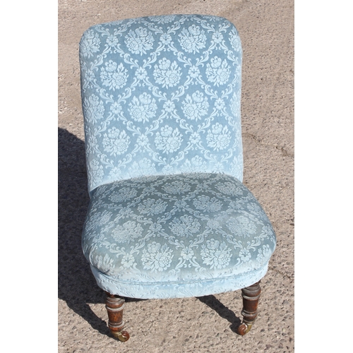 38 - A small antique blue upholstered bedroom chair with turned legs and brass & ceramic castors