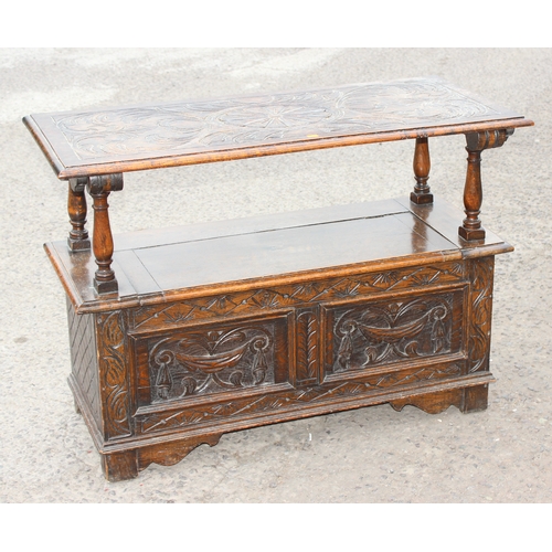 28 - An early 20th century carved oak monks bench with folding table top, approx 107cm wide x 48cm deep x... 