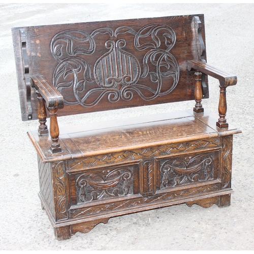 28 - An early 20th century carved oak monks bench with folding table top, approx 107cm wide x 48cm deep x... 