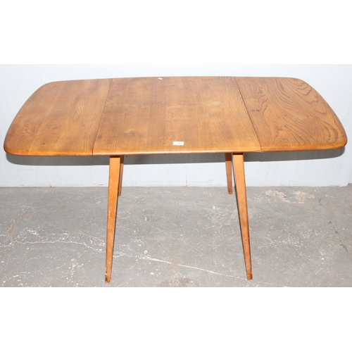 3 - A retro blonde Ercol drop leaf table, approx 138cm wide x 76cm deep x 72cm tall