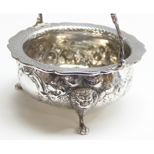 1046 - A George IV period silver basket with swing handle, embossed floral decoration with 3 lion mask and ... 