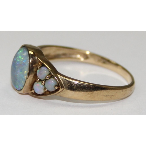 2062 - A 9ct gold oval shaped black opal triplet ring flanked by smaller opals, full English hallmarks, app... 