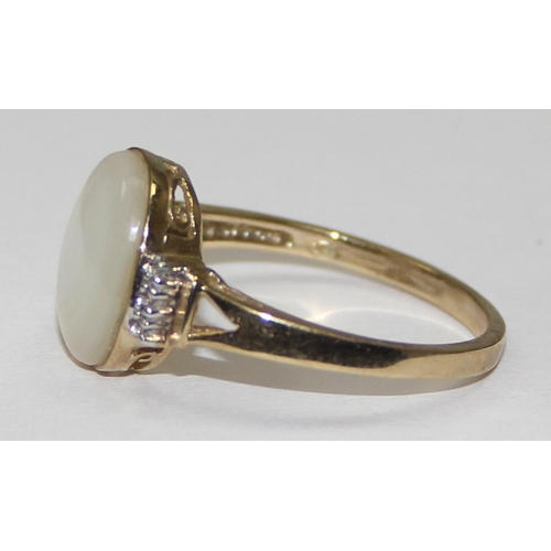 2063 - A 9ct gold oval shaped mother of pearl cabochon ring flanked by small diamonds, full English hallmar... 