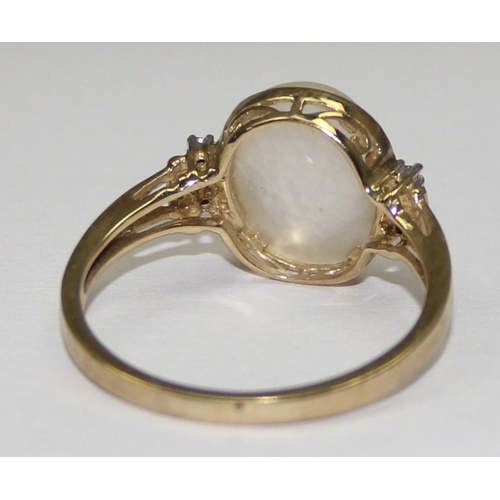 2063 - A 9ct gold oval shaped mother of pearl cabochon ring flanked by small diamonds, full English hallmar... 