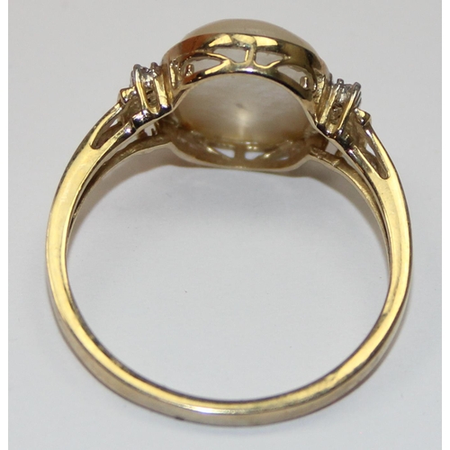 2063 - A 9ct gold oval shaped mother of pearl cabochon ring flanked by small diamonds, full English hallmar... 