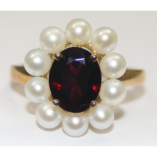 2068 - A 9ct gold floral set dress ring, a central facet cut red stone surrounded by 10 small pearls, full ... 