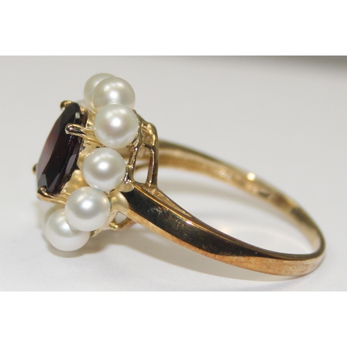 2068 - A 9ct gold floral set dress ring, a central facet cut red stone surrounded by 10 small pearls, full ... 