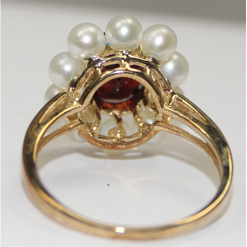 2068 - A 9ct gold floral set dress ring, a central facet cut red stone surrounded by 10 small pearls, full ... 