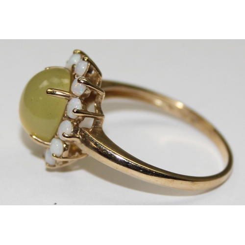 2069 - A 9ct gold dress ring, a central cloudy green cabochon stone surrounded by 12 small opals, full Engl... 