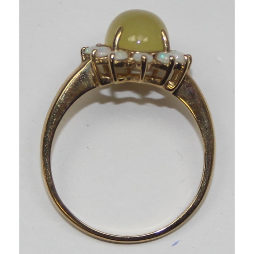 2069 - A 9ct gold dress ring, a central cloudy green cabochon stone surrounded by 12 small opals, full Engl... 