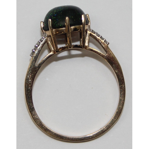 2072 - A retro style 9ct gold dress ring, a round dark cabochon aventurine like stone flanked by small diam... 