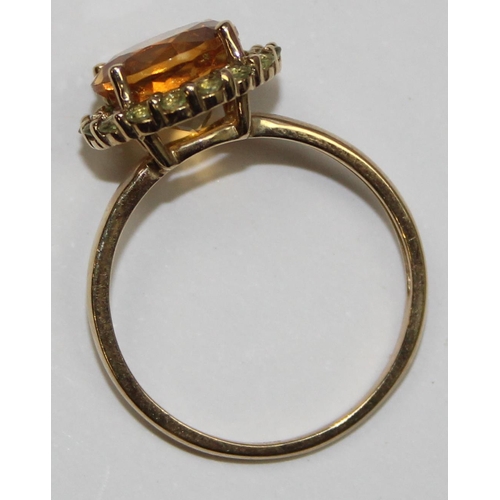 2077 - A 9ct gold citrine dress ring, a large facet cut round central stone surrounded by small white stone... 