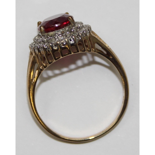 2083 - A 9ct gold deep red pink stone cocktail ring surrounded by small diamonds, full English hallmarks, a... 