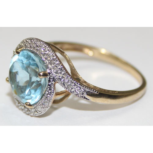 2085 - A 9ct gold retro style light blue stone cocktail ring surrounded by small diamonds in a crossover se... 