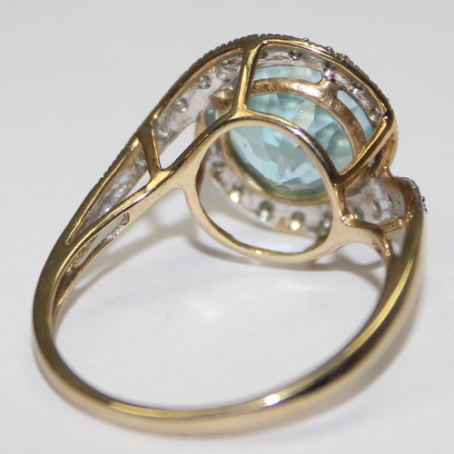 2085 - A 9ct gold retro style light blue stone cocktail ring surrounded by small diamonds in a crossover se... 