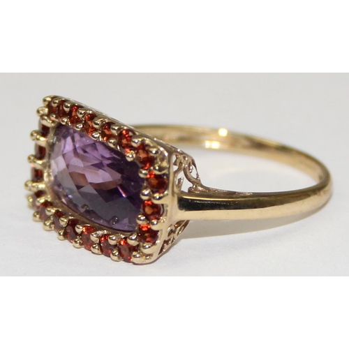 2093 - A 9ct gold Georgian style ring in decorative mounting, a large facet cut light purple stone surround... 