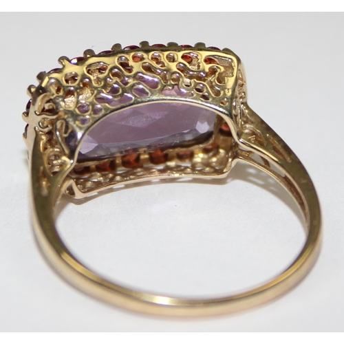 2093 - A 9ct gold Georgian style ring in decorative mounting, a large facet cut light purple stone surround... 