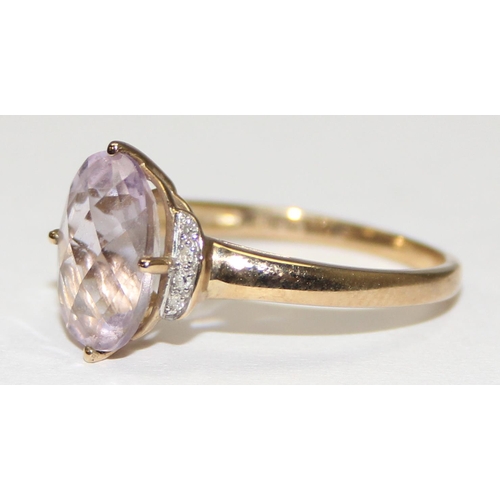 2113 - A 9ct gold ring comprising of a light purple stone flanked by small diamonds, full English hallmarks... 