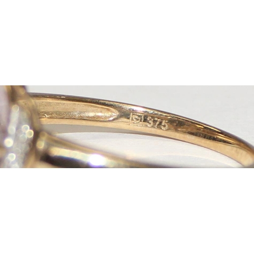 2113 - A 9ct gold ring comprising of a light purple stone flanked by small diamonds, full English hallmarks... 