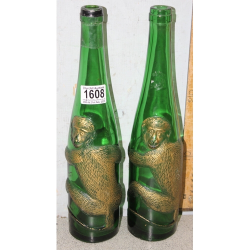 1608 - A pair of vintage embossed and gilt green glass bottles decorated with a clinging monkey, each appro... 