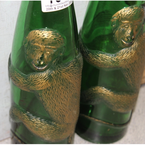 1608 - A pair of vintage embossed and gilt green glass bottles decorated with a clinging monkey, each appro... 