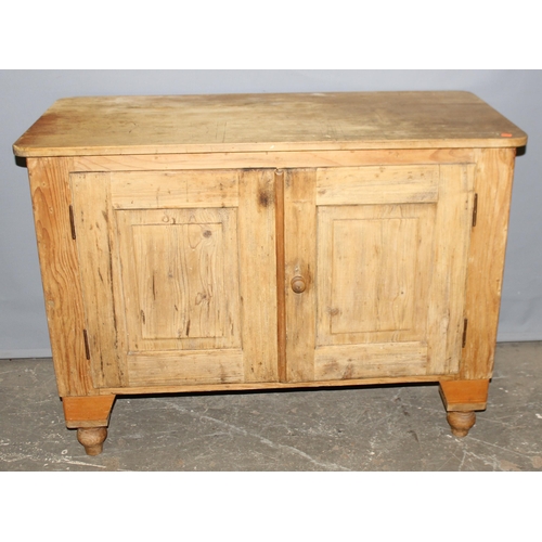 12 - An antique pine cupboard or sideboard, 2 doors opening to reveal a single shelf, standing on turned ... 