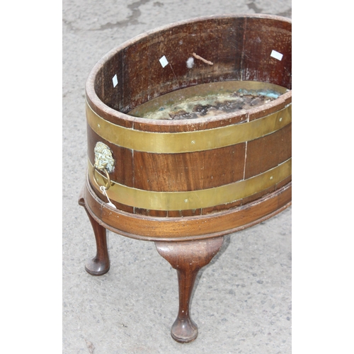 11 - A George III mahogany oval and brass bound wine cooler, circa 1780, now as a jardiniere, with lions ... 