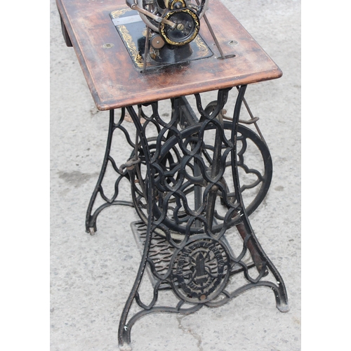 22 - An antique Singer sewing machine table with cast iron base, complete with machine