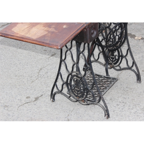 22 - An antique Singer sewing machine table with cast iron base, complete with machine