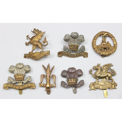 1411 - Military cap badges - 7 assorted military cap badges all relating to the Wales, to include The Buffs... 