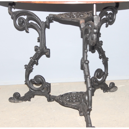 108 - A vintage wooden topped pub table with decorative wrought iron base, approx 91cm round x 74cm tall