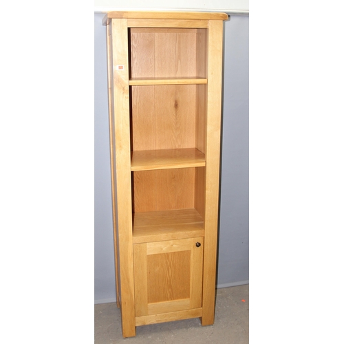 29 - A tall slim modern light oak bookcase with cupboard, likely from Oak Furnitureland, approx 63cm wide... 