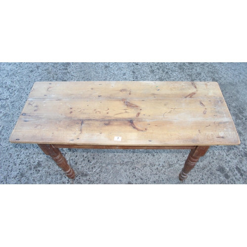 7 - An unusual rustic pine table of slim proportions standing on turned legs, approx 131cm wide x 49cm d... 