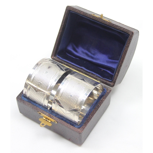 1024 - A pair of antique silver plated napkin rings in original leather case, each engraved with belt buckl... 