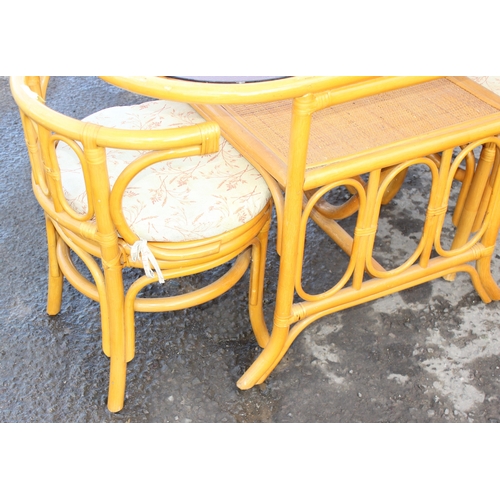 55 - A retro bamboo and tempered smoked glass bistro table and 2 chairs, the table approx 110cm W x 57cm ... 