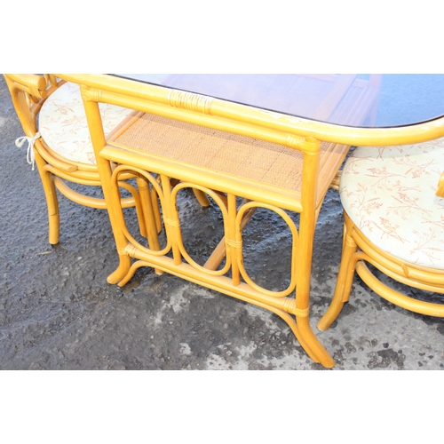 55 - A retro bamboo and tempered smoked glass bistro table and 2 chairs, the table approx 110cm W x 57cm ... 