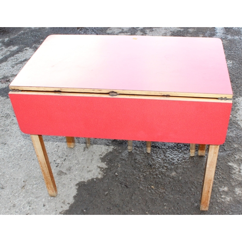 54 - A small mid-century Formica topped table with small drop flap and 2 drawers, and retro stools, the t... 