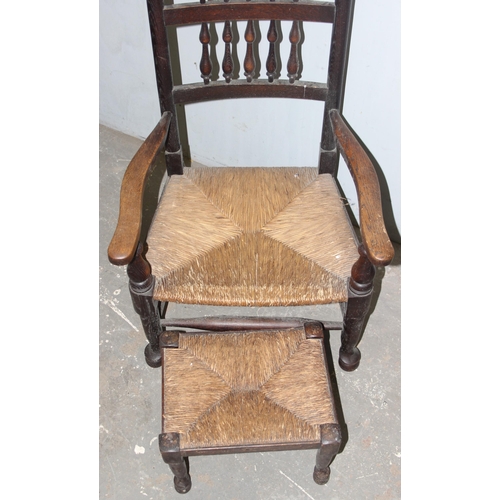 121 - An Arts & Crafts period oak armchair with rush seat and a matching footstool