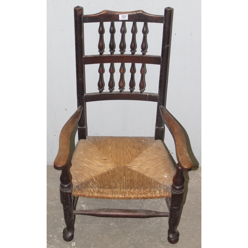 121 - An Arts & Crafts period oak armchair with rush seat and a matching footstool