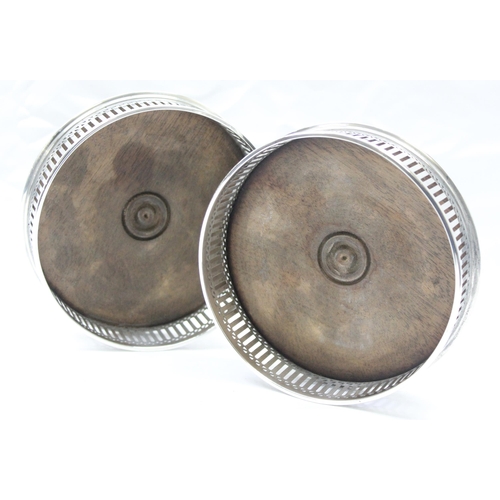 1094 - A pair of pierced silver and wooden wine bottle coasters, London 1984 by WEV, each approx 13cm in di... 