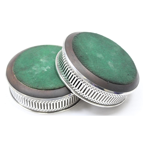 1094 - A pair of pierced silver and wooden wine bottle coasters, London 1984 by WEV, each approx 13cm in di... 