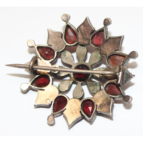 1146 - A Georgian style star shaped Garnet cluster brooch comprised of three tiers of mixed cut garnets in ... 