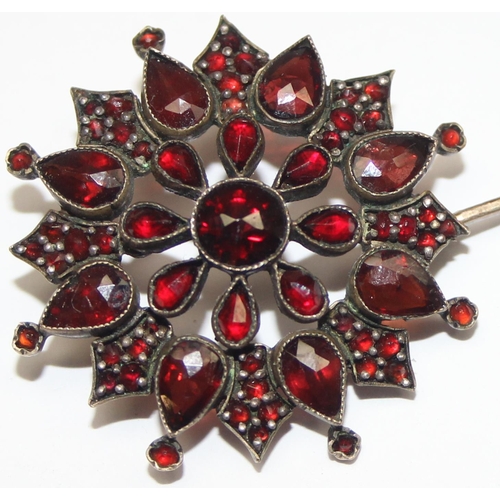 1146 - A Georgian style star shaped Garnet cluster brooch comprised of three tiers of mixed cut garnets in ... 