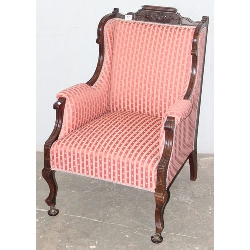 52 - A 19th century high backed armchair with striped upholstery and mahogany frame with carved details