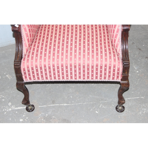 52 - A 19th century high backed armchair with striped upholstery and mahogany frame with carved details