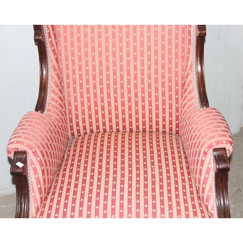 52 - A 19th century high backed armchair with striped upholstery and mahogany frame with carved details