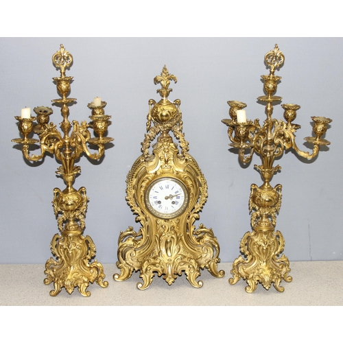 1321 - A highly decorative French brass clock garniture, a highly decorative Rococo style clock flanked by ... 